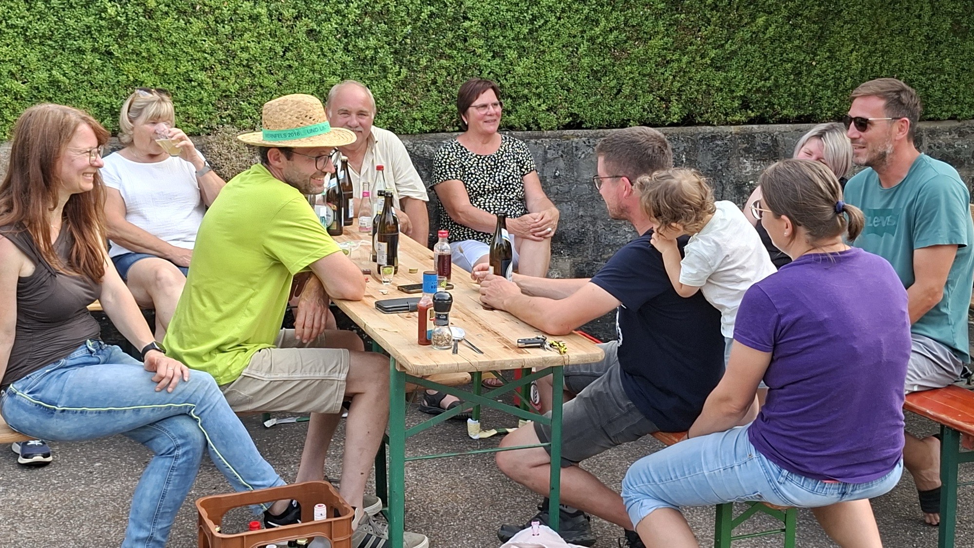 Fröhliche Runde an einem Biertisch vor der Hecke