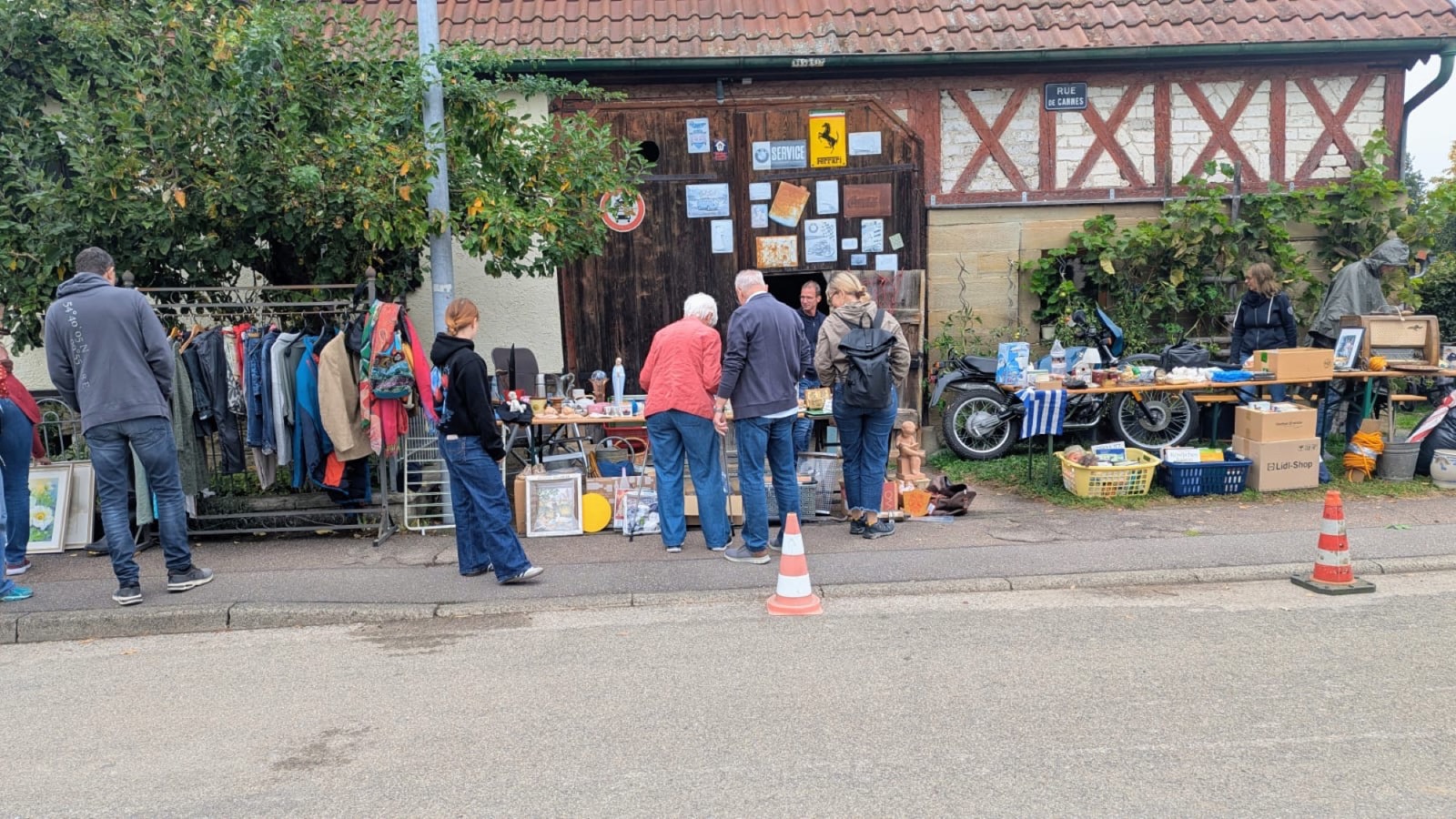 Stand mit Kleidern und Trödel vor einer Fachwerkscheune
