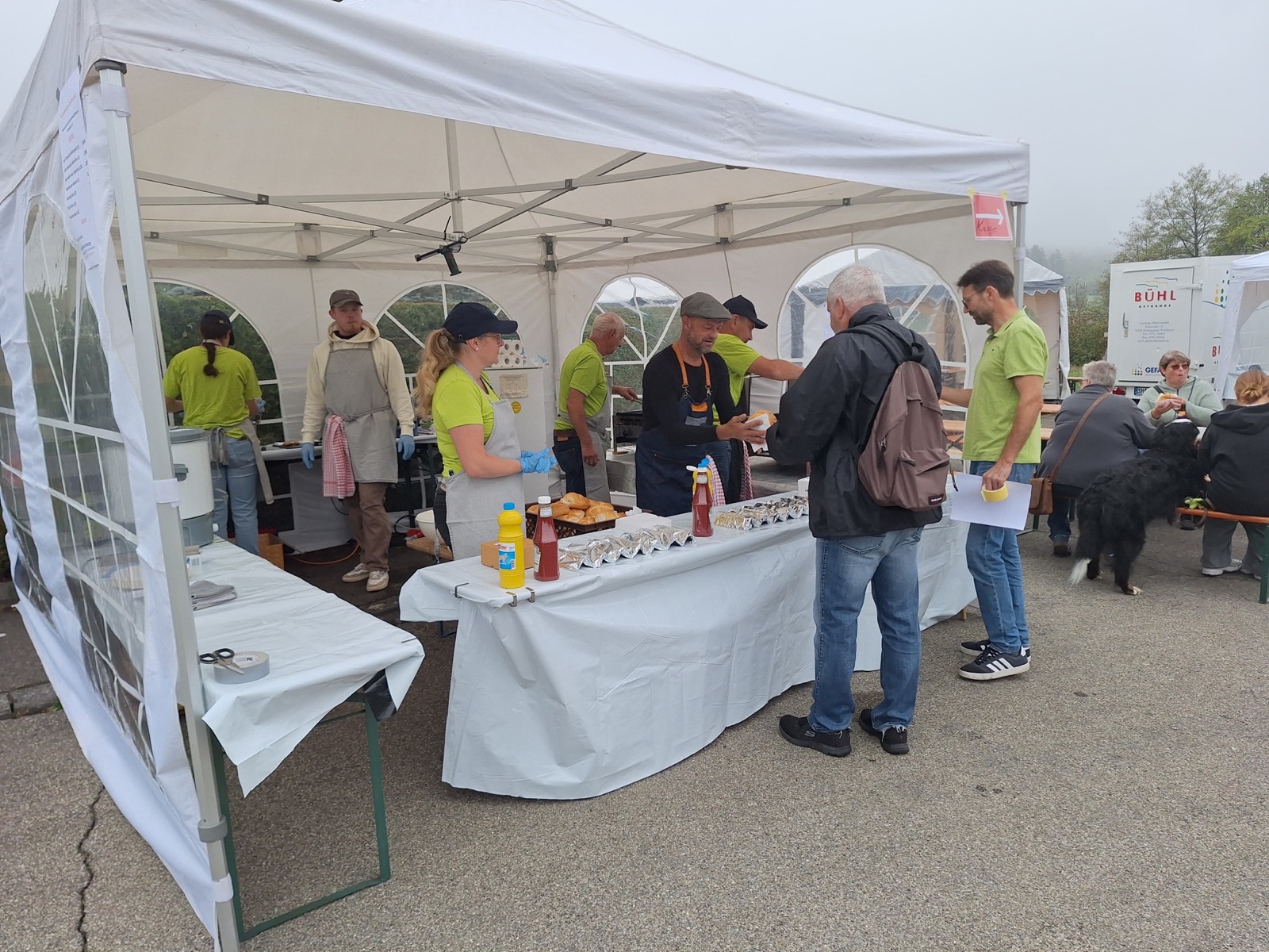 Grillstand mit Helferinnen und Helfern im Zelt